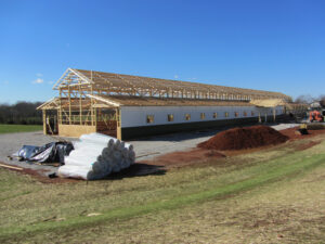 Post-frame barn with wood framework and material in the foreground.