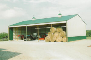 Post-frame storage building with bails of hay and equipment.
