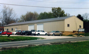 Long post-frame office building with five cars parked in front.