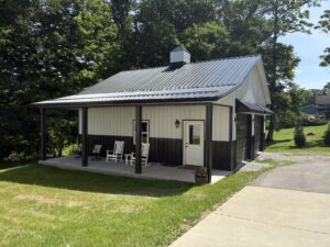 Post frame construction home with front porch, green roof, and beige color